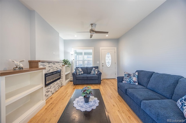 living area with recessed lighting, light wood-style floors, ceiling fan, and a glass covered fireplace