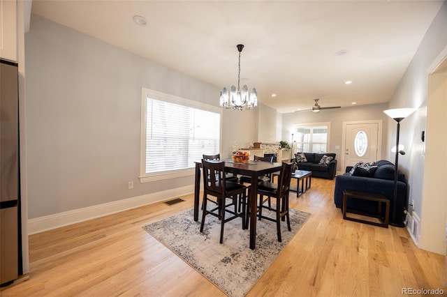 dining space featuring light wood-style flooring, recessed lighting, ceiling fan with notable chandelier, visible vents, and baseboards