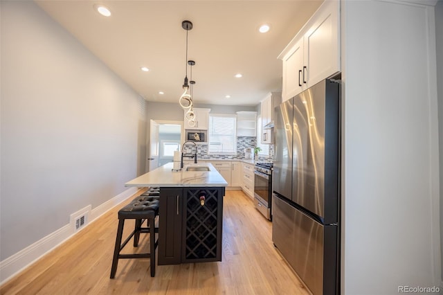 kitchen with stainless steel appliances, backsplash, a sink, and white cabinets