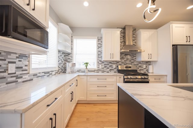 kitchen with stainless steel appliances, wall chimney range hood, plenty of natural light, and open shelves