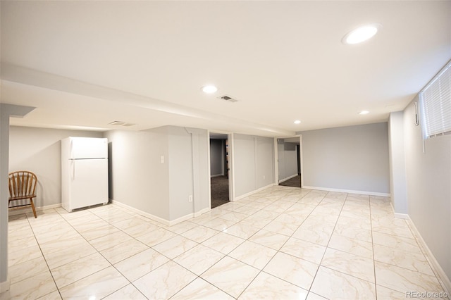 finished below grade area with visible vents, recessed lighting, freestanding refrigerator, and baseboards