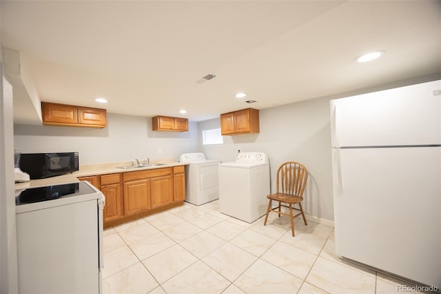 kitchen featuring black microwave, separate washer and dryer, stove, visible vents, and freestanding refrigerator