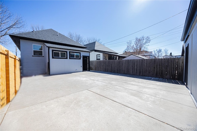 view of home's exterior featuring a shingled roof, a fenced backyard, a patio, and brick siding