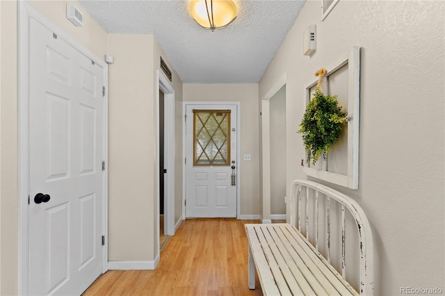 hall with light hardwood / wood-style floors and a textured ceiling