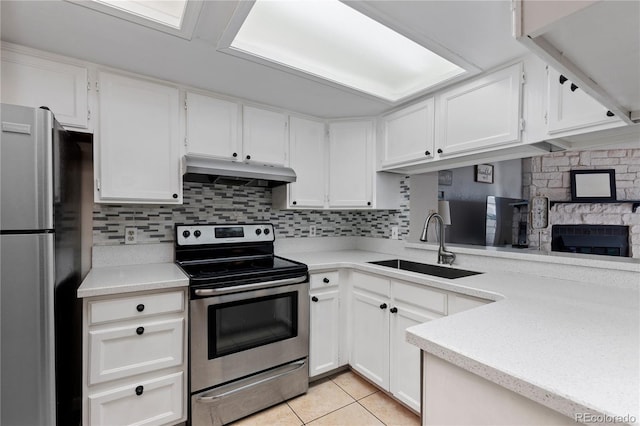 kitchen with light tile patterned flooring, sink, appliances with stainless steel finishes, white cabinets, and backsplash