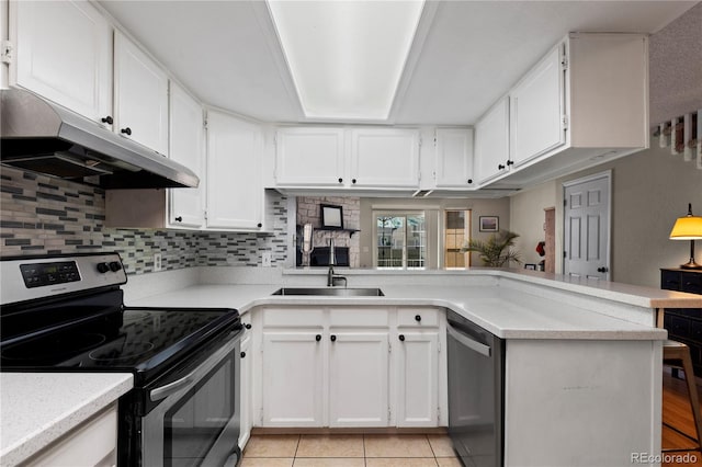 kitchen with appliances with stainless steel finishes, white cabinetry, sink, light tile patterned floors, and kitchen peninsula