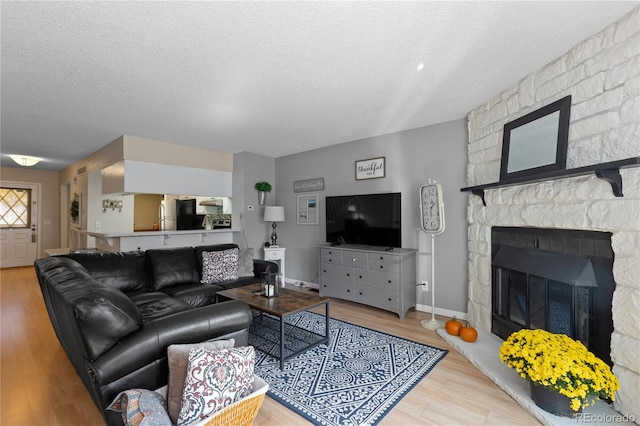 living room with a fireplace, a textured ceiling, and light wood-type flooring