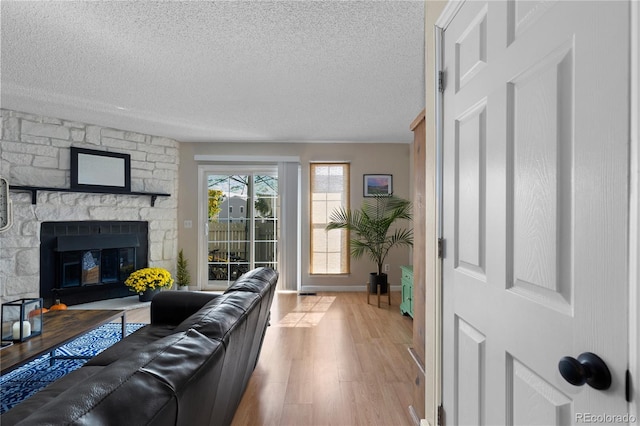 living room featuring a fireplace, light hardwood / wood-style floors, and a textured ceiling