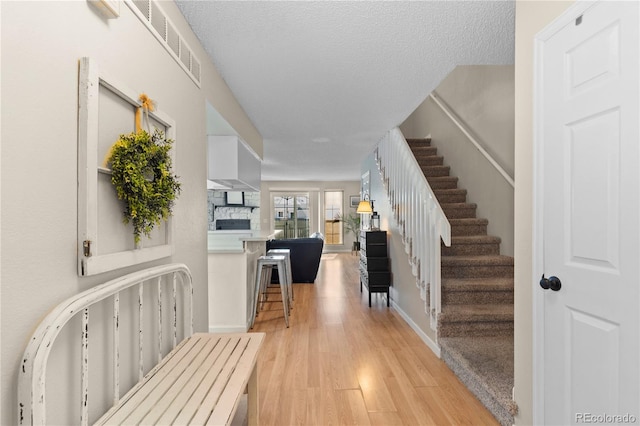 entryway featuring a fireplace, a textured ceiling, and light wood-type flooring