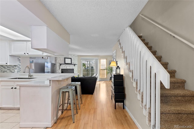 kitchen with sink, white cabinets, a kitchen bar, decorative backsplash, and a textured ceiling