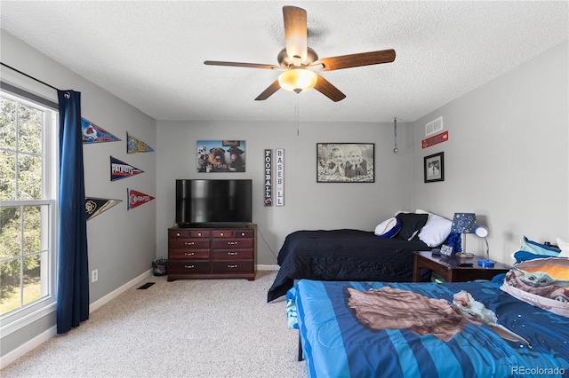 bedroom with ceiling fan, light colored carpet, and a textured ceiling