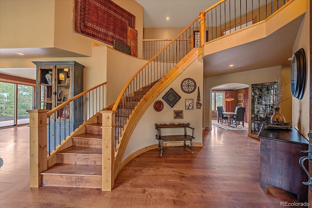 1456 Shavano Ct, Evergreen, CO 80439 - stairway featuring a towering ceiling, arched walkways, healthy amount of natural light, wood finished floors, and recessed lighting