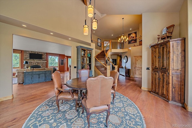 1456 Shavano Ct, Evergreen, CO 80439 - dining area featuring a chandelier, wood finished floors, high vaulted ceiling, a stone fireplace, and stairs