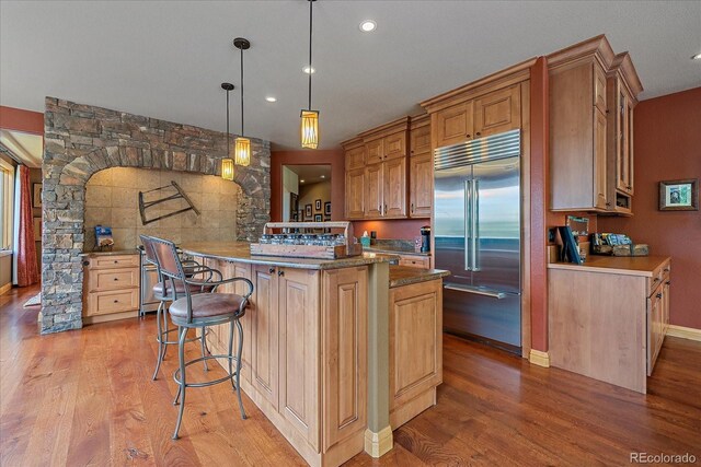 1456 Shavano Ct, Evergreen, CO 80439 - kitchen with stainless steel built in refrigerator, light wood-style floors, a kitchen breakfast bar, recessed lighting, and decorative light fixtures