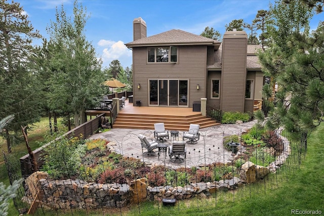 1456 Shavano Ct, Evergreen, CO 80439 - back of property featuring a chimney, a patio, a wooden deck, and roof with shingles