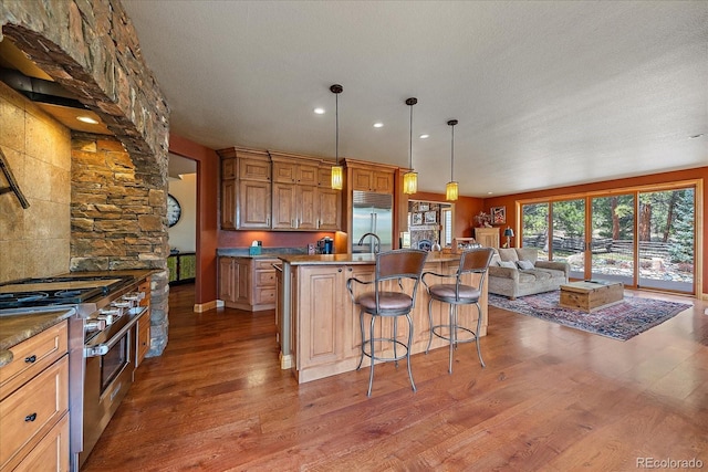 1456 Shavano Ct, Evergreen, CO 80439 - kitchen featuring high quality appliances, open floor plan, wood finished floors, a kitchen bar, and recessed lighting