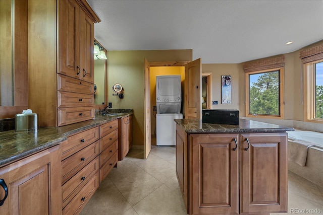 1456 Shavano Ct, Evergreen, CO 80439 - bathroom with stacked washer / dryer, vanity, tile patterned flooring, and a bathtub
