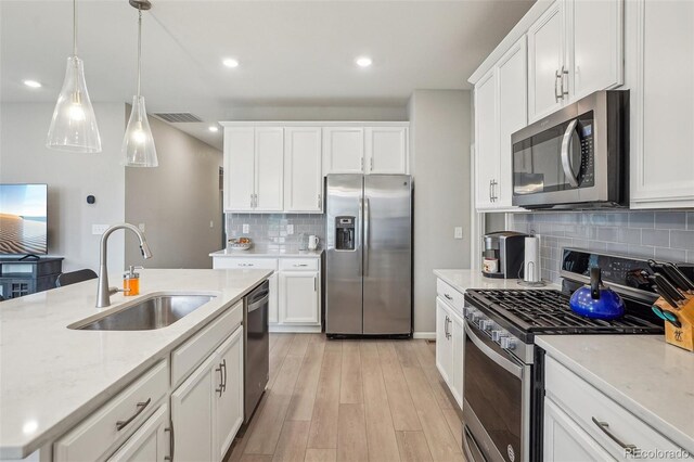 5928 N Odessa St, Aurora, CO 80019 - kitchen featuring stainless steel appliances, a sink, decorative backsplash, light wood finished floors, and white cabinetry