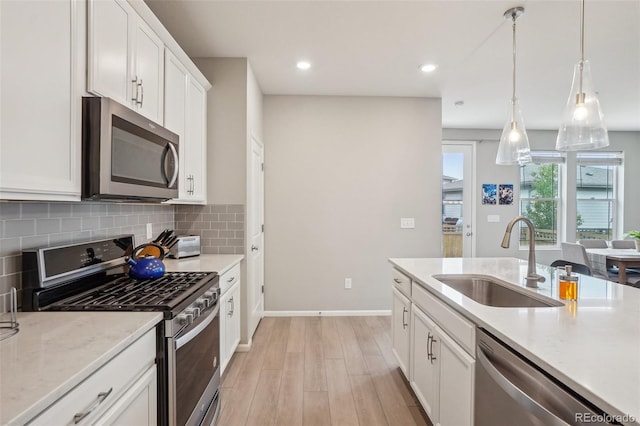 5928 N Odessa St, Aurora, CO 80019 - kitchen with appliances with stainless steel finishes, a sink, light wood-style floors, decorative backsplash, and white cabinetry