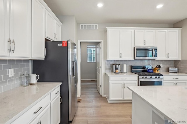 5928 N Odessa St, Aurora, CO 80019 - kitchen with appliances with stainless steel finishes, light wood-type flooring, white cabinets, decorative backsplash, and light stone counters