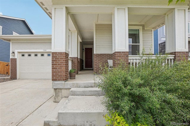 5928 N Odessa St, Aurora, CO 80019 - entrance to property featuring covered porch, brick siding, a garage, and driveway
