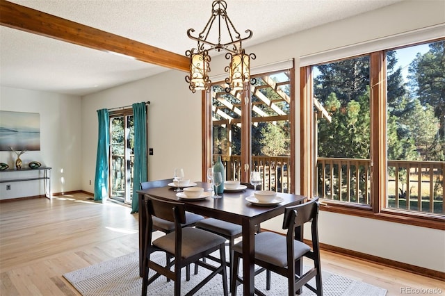 dining space featuring beam ceiling, a textured ceiling, and light hardwood / wood-style flooring