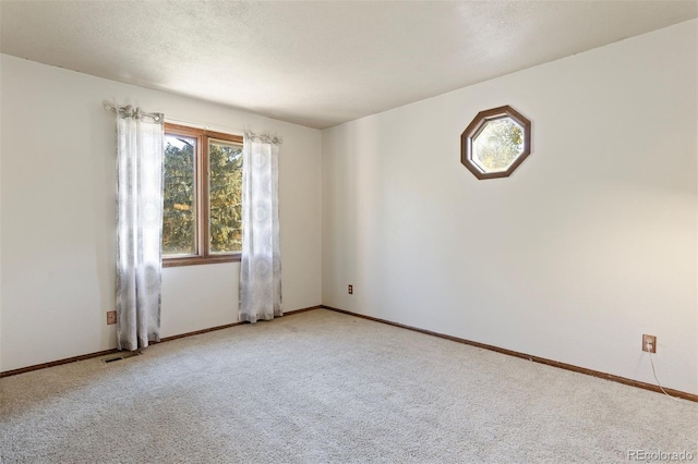 carpeted empty room featuring a textured ceiling