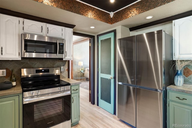 kitchen featuring backsplash, stainless steel appliances, white cabinetry, and light hardwood / wood-style floors