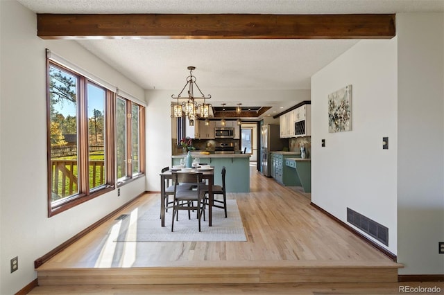 dining room featuring beam ceiling, light hardwood / wood-style flooring, a textured ceiling, and a notable chandelier