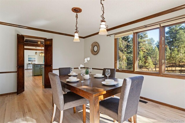 dining room featuring light wood-type flooring and crown molding