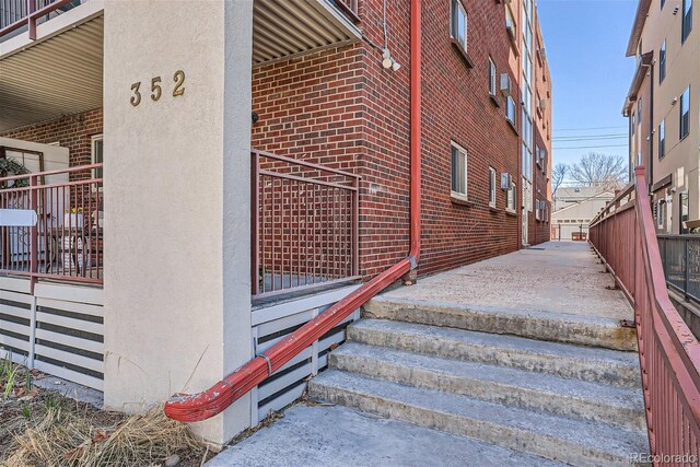doorway to property featuring brick siding and fence