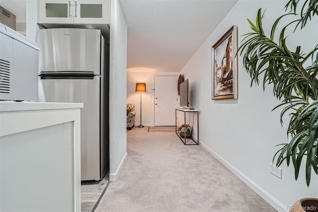 hallway featuring light carpet and baseboards
