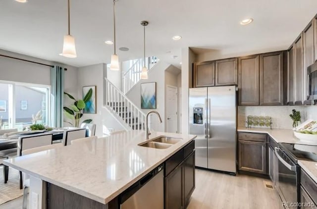 2094 Wagon Wheel Aly, Brighton, CO 80601 - kitchen featuring appliances with stainless steel finishes, light wood-type flooring, dark brown cabinets, an island with sink, and pendant lighting