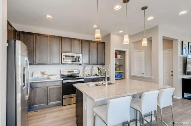 2094 Wagon Wheel Aly, Brighton, CO 80601 - kitchen with appliances with stainless steel finishes, light wood-style floors, hanging light fixtures, light stone countertops, and recessed lighting