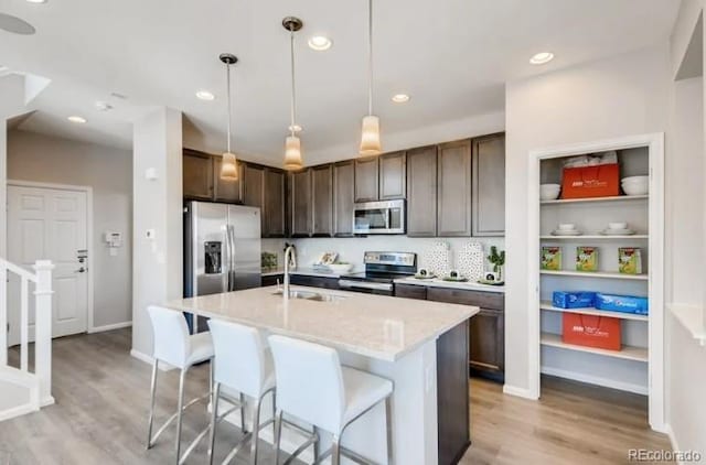 2094 Wagon Wheel Aly, Brighton, CO 80601 - kitchen with appliances with stainless steel finishes, light wood-style flooring, dark brown cabinets, a kitchen bar, and hanging light fixtures