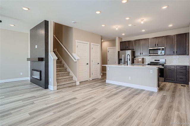2436 W 69th Pl, Denver, CO 80221 - kitchen featuring appliances with stainless steel finishes, light countertops, dark brown cabinets, light wood-style floors, and decorative backsplash