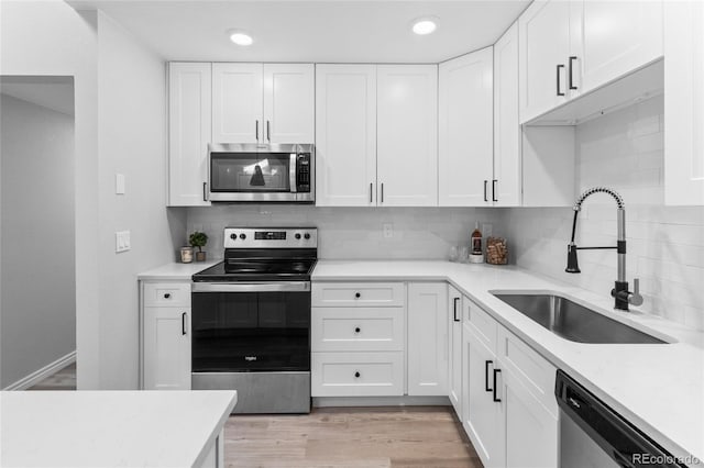 kitchen featuring backsplash, white cabinetry, sink, and stainless steel appliances