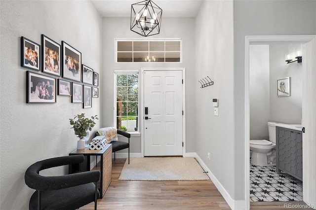 entryway with a chandelier, wood finished floors, and baseboards