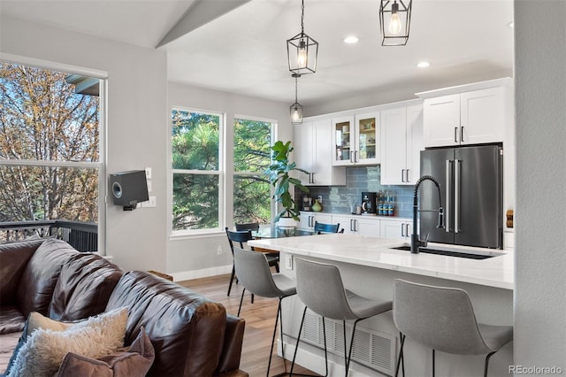 kitchen featuring high quality fridge, open floor plan, tasteful backsplash, a breakfast bar, and white cabinets