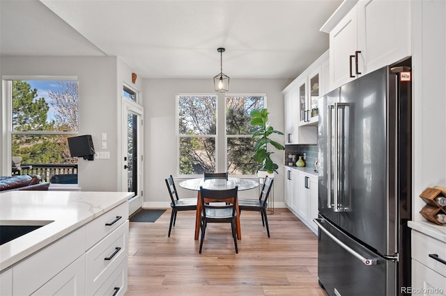 kitchen with high end fridge, light wood-style flooring, white cabinets, backsplash, and glass insert cabinets