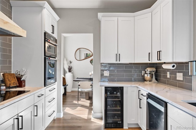 kitchen with wine cooler, extractor fan, light wood-type flooring, white cabinetry, and backsplash