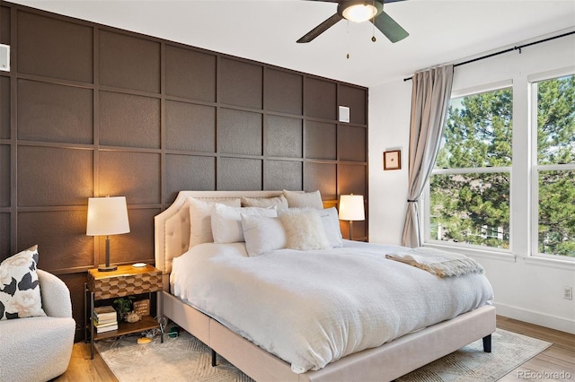 bedroom featuring multiple windows, wood finished floors, baseboards, and a ceiling fan