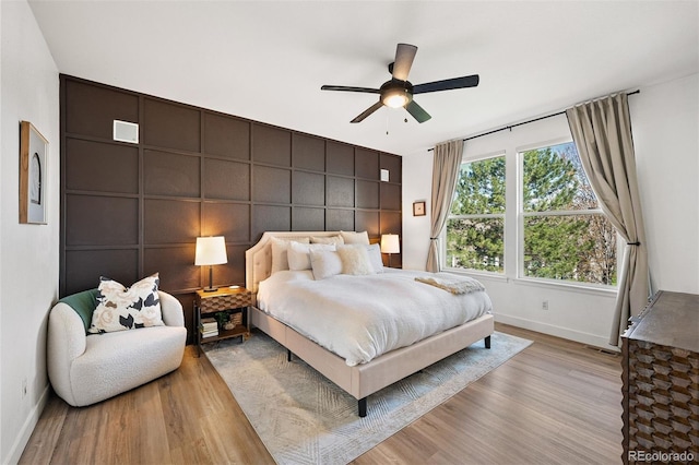 bedroom featuring baseboards, wood finished floors, and a ceiling fan