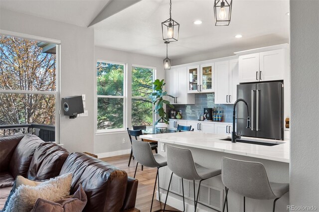 1053 Snow Lily Ct, Castle Pines, CO 80108 - kitchen featuring high quality fridge, open floor plan, tasteful backsplash, a breakfast bar, and white cabinets