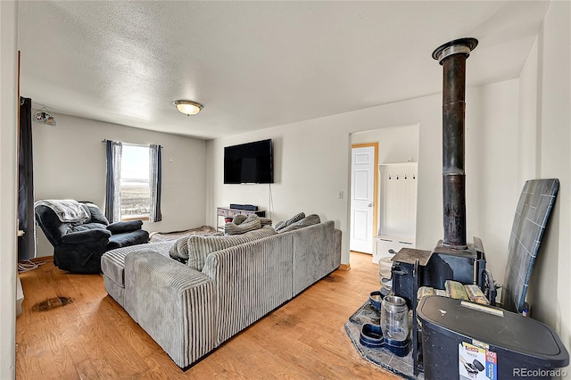 living room with a wood stove, light wood finished floors, and a textured ceiling