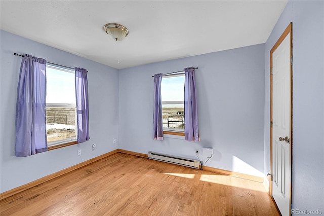 spare room featuring plenty of natural light, wood finished floors, baseboards, and a baseboard radiator