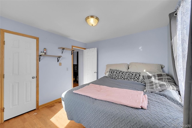 bedroom with light wood finished floors and baseboards