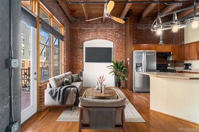 living room with beam ceiling, light wood-style flooring, wooden ceiling, a ceiling fan, and a towering ceiling