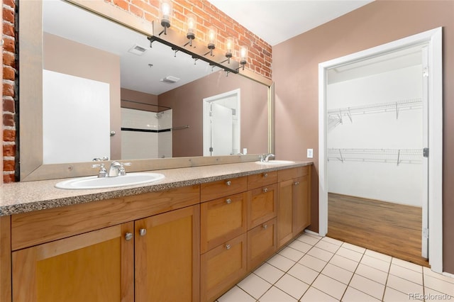 full bath featuring tile patterned flooring, a shower, a spacious closet, and double vanity