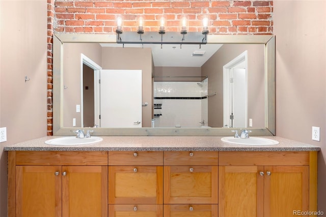 bathroom featuring a shower with door, double vanity, and brick wall